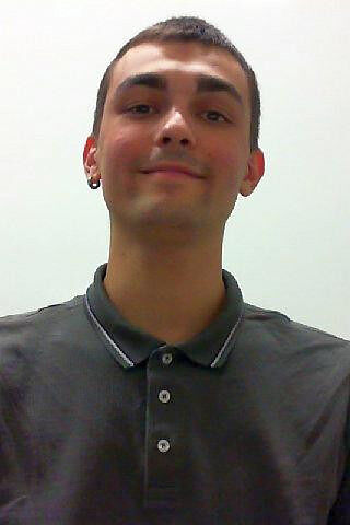 Portrait photo of a young man with short dark hair wearing a dark polo shirt, facing forward with a slight smile